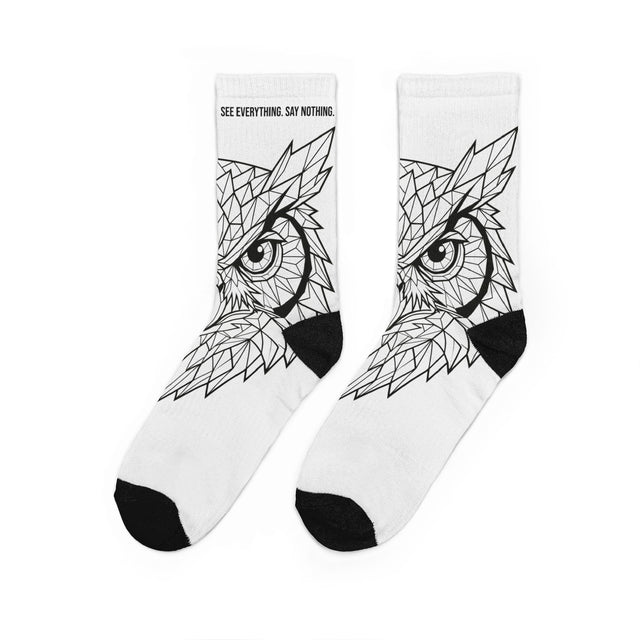 White socks with black owl design and text 'See Everything Say Nothing' on a white background