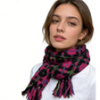 Close-up image of a woman wearing a vibrant woven scarf featuring a colorful pattern with pink, black, green, and purple hues, paired with a simple white top, highlighting a cozy and stylish winter accessory. | PicSEO 1775591618800