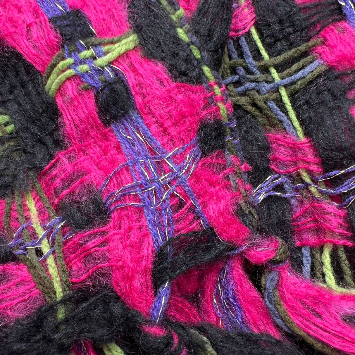 Close-up image of a vibrant woven textile featuring a mix of bright pink, black, green, and purple yarns. The intricate texture showcases intertwined fibers and layered threads, highlighting the craftsmanship and detailed pattern of the fabric. | PicSEO 1775591650622